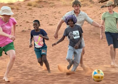 interns playing football with children