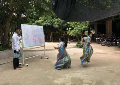 Two children playing near a teacher.