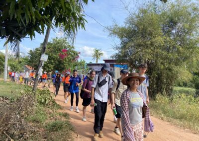 A long line of people walking down a dirt path.